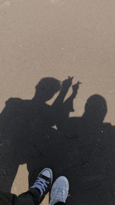 two people standing next to each other with their shadows on the ground and one person holding a cell phone