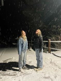 two people standing in the snow with their eyes closed and one person looking up at something