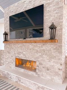 a fireplace with a flat screen tv above it and two lanterns on the mantles