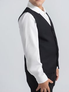 Our tailored black tux vest adds the finishing touches to a 3 piece suit. Buttons can be left button or unbuttoned. Pair with matching black double breasted blazer and black tailored dress pants for a sharp effortless look. Explore Mofi Clothing: meticulously crafted for husky, broader, and stout boys, or any boy who simply needs a bit more room. Our designs prioritize comfort without compromising on style, ensuring every child feels confident and comfortable. Model 1 wearing size 12. Model 2 we Classic Black Vest For Business, Formal Fitted Black Vest, Black Fitted Formal Vest, Black Fitted Vest For Formal Occasions, Classic Black Tuxedo With Single Button, Classic Black Three-piece Suit For Black-tie Events, Classic Black Single-button Tuxedo, Classic Black Tailoring Vest, Classic Black Vest For Tailoring