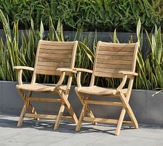 two wooden chairs sitting next to each other in front of a planter filled with succulents