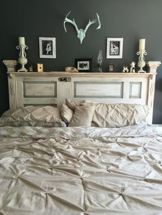 the bed is made with white linens and has antlers on it's headboard