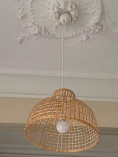 a light fixture hanging from the ceiling in a room with white paint and plaster work