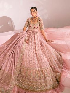 a woman in a pink gown and veil posing for the camera with her hands on her hips