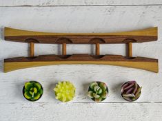 four succulents are arranged on a wooden rack