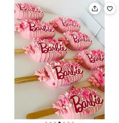 some pink cake pops are on a white table and one is decorated with the word barbie