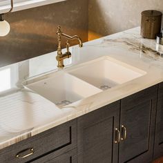 a kitchen with marble counter tops and two sinks in the center, under a window