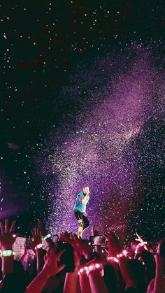 a man standing on top of a stage surrounded by people holding their hands in the air