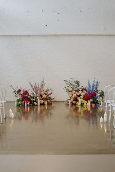 a couple of white chairs sitting next to each other with flowers and candles on them