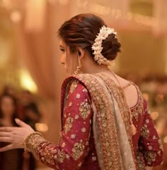 a woman in a red and gold bridal gown is holding her hands out to the side