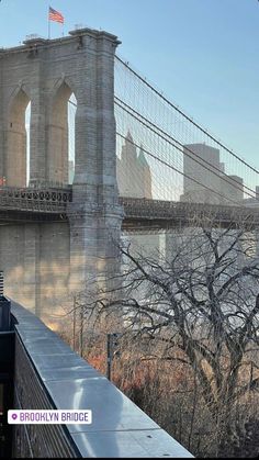 a train passing by the brooklyn bridge in new york city, with an american flag on it