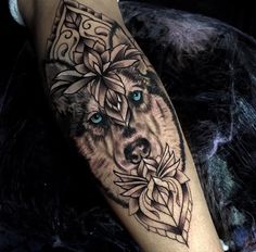 a black and white tattoo with a wolf on it's arm, surrounded by flowers