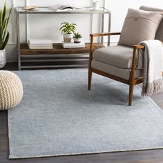 a living room area with a chair, rug and potted plant on the floor