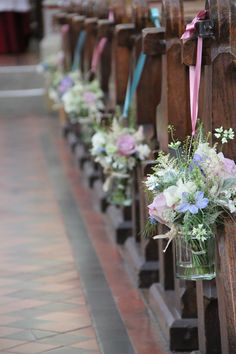 rows of wooden pews with flowers and ribbons tied to the sides, along side each other