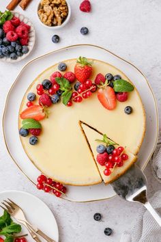 a cheesecake topped with berries and blueberries sits on a plate next to other desserts