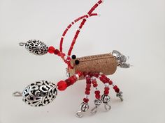 a wine bottle with red beads and charms attached to it is sitting on a white surface