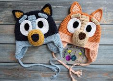 two crocheted hats with eyes and ears on top of wooden planked surface