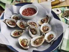 several oysters on a plate with a small bowl of dipping sauce