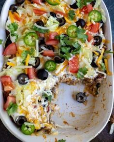 a white plate topped with a taco casserole covered in cheese and black olives