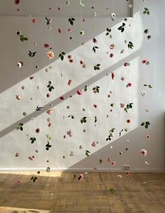 a white wall with flowers hanging from it's side and a window in the background