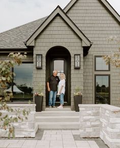 a man and woman standing in front of a house