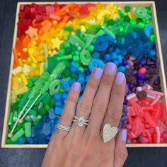 a woman's hand with two rings on her fingers next to a rainbow background