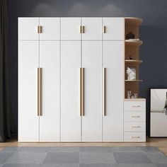 a white cabinet with gold handles next to a gray rug and black wall behind it