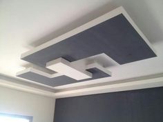 an empty room with white and grey painted ceiling tiles on the ceiling, along with a window