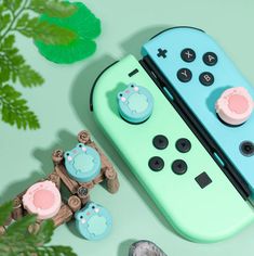 a nintendo wii game controller next to a plant and some toys on a table with green leaves