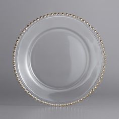 a white plate with gold beading on the rim and bottom, against a gray background