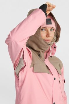 a woman in a pink jacket holding her hood up