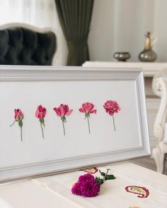 pink flowers are placed in front of a white frame