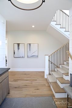 an open floor plan with stairs leading up to the second floor and two paintings on the wall