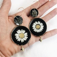 24k gold plated round dangle statement earrings made with real pressed flowers set in black resin. The small circle contains queen anne's lace, and the large circle contains a daisy. *Model is wearing this style in the clear resin. This listing is for the Daisy dangles with black resin. Perfect for nature lovers! These preserved botanical earrings are super lightweight and will make a statement! Pendants/charms: 24k gold plated brass Earring hoops: gold plated brass Thanks for shopping handmade! Bohemian Dangle Jewelry With Pressed Flowers, Flower Shaped Brass Jewelry With Matching Earrings, Bohemian Black Flower Earrings For Gift, Brass Flower Earrings With Charm As Gift, Brass Flower Charm Earrings For Gifts, Elegant Pressed Flower Drop Earrings, Brass Flower Earrings For Gift, Brass Round Flower Earrings, Round Flower Earrings As A Gift For Her