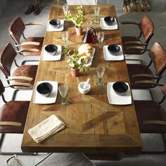 a wooden table topped with lots of white plates and place settings on top of it