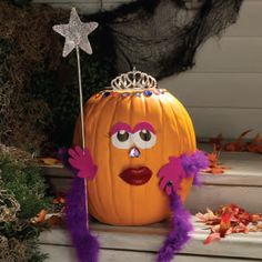 a pumpkin with a tiara on it sitting in front of a star and other decorations