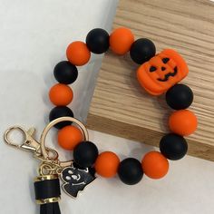 an orange and black beaded bracelet with a carved jack - o - lantern charm