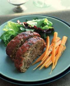 meatloaf, carrots and lettuce on a blue plate with a glass of wine