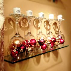 several wine glasses are lined up on a shelf with christmas ornaments in front of them