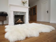 a white sheepskin rug is on the floor in front of a fireplace