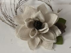 a close up of a flower on a white surface with some branches in the background