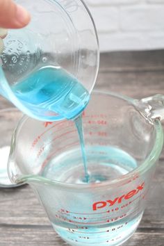 someone pouring blue liquid into a measuring cup