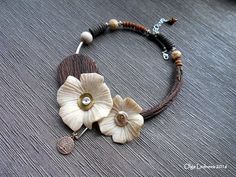 a bracelet with two flowers and a coin hanging from it's side on a table