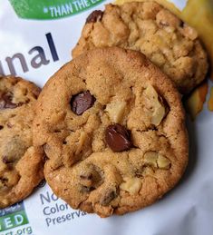 three chocolate chip cookies sitting on top of a bag