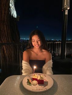 a woman sitting at a table in front of a birthday cake with lit candles on it