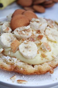 a dessert with bananas and other toppings sits on a plate next to almonds