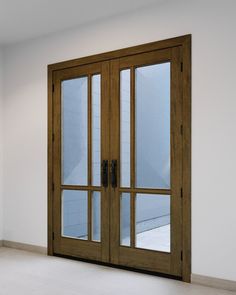 an empty room with wooden doors and white walls, in front of a large window