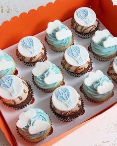 a box filled with cupcakes covered in frosting and blue icing on top of each other