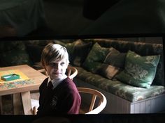 a young boy sitting at a table in front of a couch