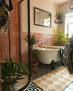 a bath tub sitting in the middle of a bathroom next to a mirror and potted plants